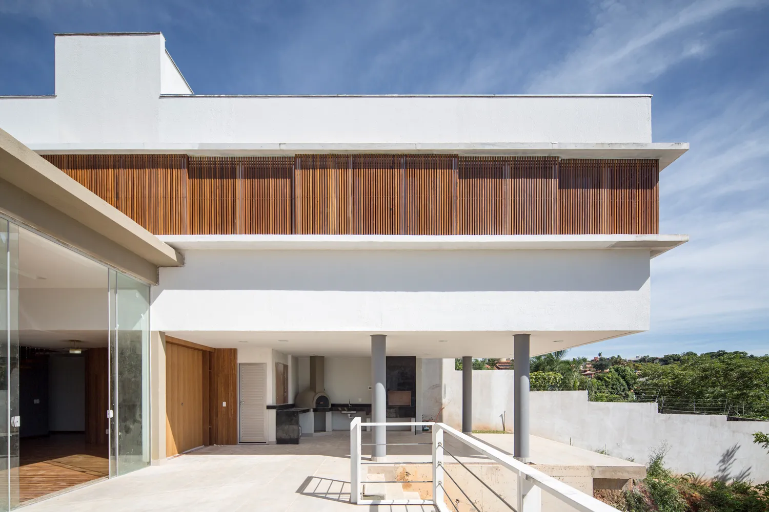 Residência com volumes brancos e brise de madeira